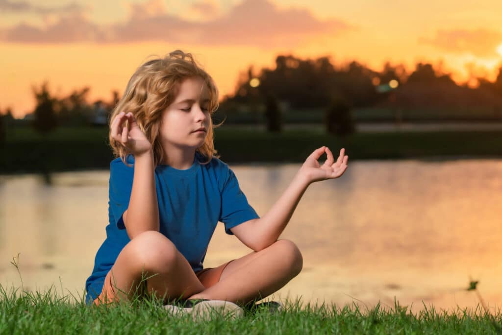 child-meditating-lotus-pose-lake